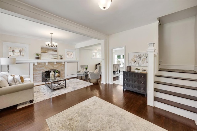 living room featuring a notable chandelier, ornamental molding, a fireplace, and dark hardwood / wood-style flooring