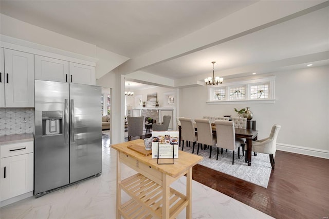 kitchen with a notable chandelier, decorative light fixtures, stainless steel fridge, and white cabinets