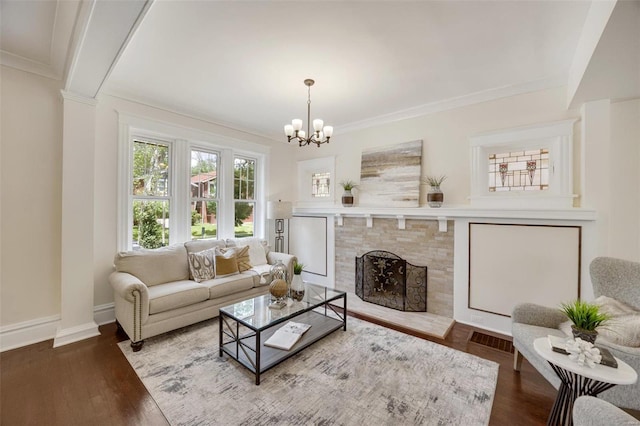 living room featuring wood-type flooring, an inviting chandelier, a fireplace, and crown molding