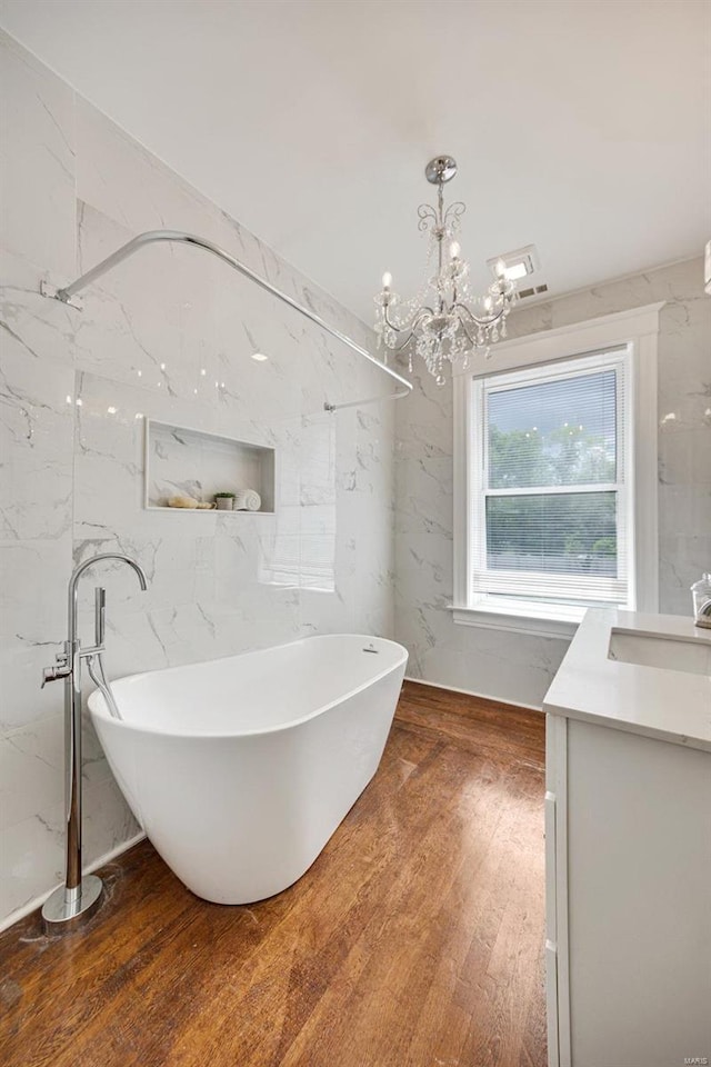 bathroom with wood-type flooring, a chandelier, vanity, and a bathtub