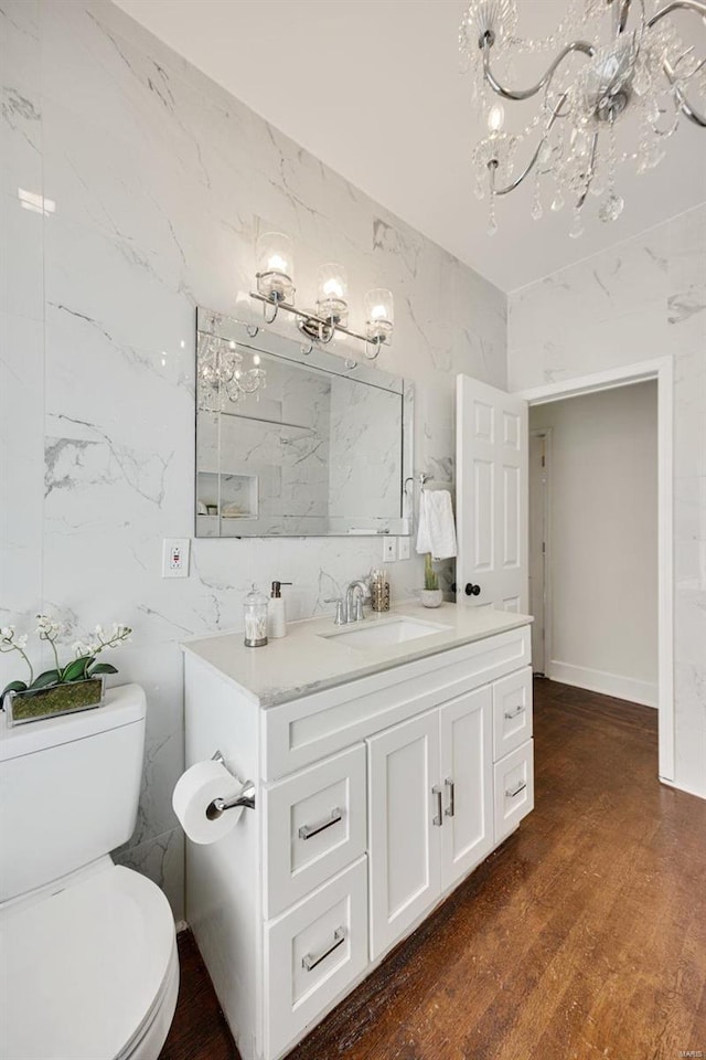 bathroom featuring vanity, wood-type flooring, toilet, and a chandelier