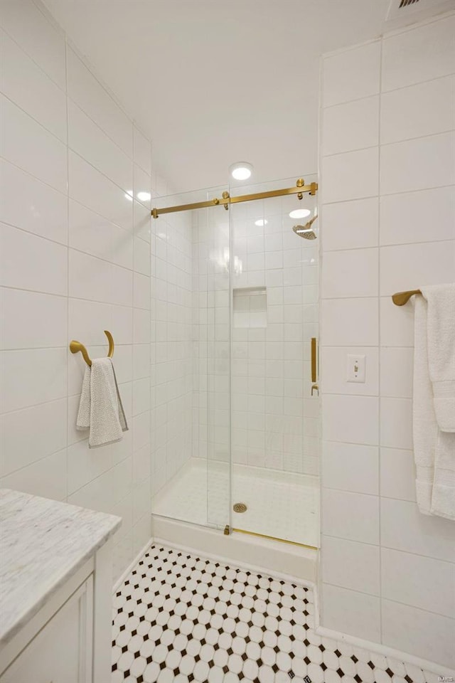 bathroom with a shower with door, tile walls, and tile patterned floors