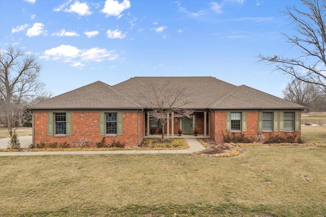 ranch-style home featuring brick siding, roof with shingles, and a front yard