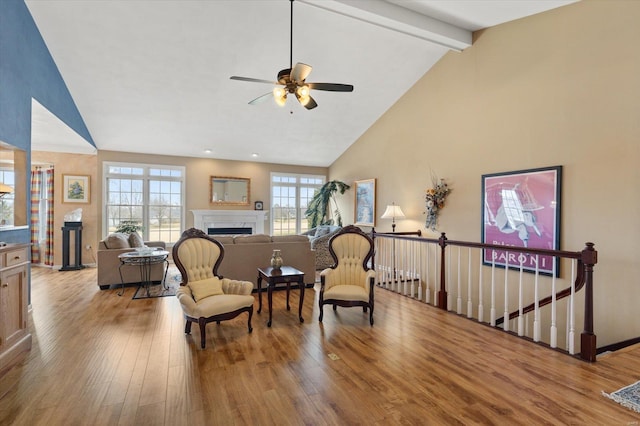 living area featuring wood finished floors, an upstairs landing, a fireplace, high vaulted ceiling, and beam ceiling