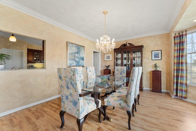 dining area featuring crown molding, light wood-style flooring, and baseboards