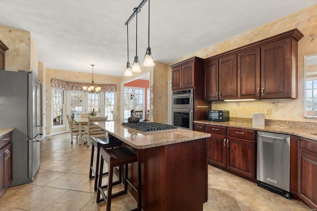 kitchen with stainless steel appliances, a center island, a kitchen breakfast bar, light stone countertops, and decorative light fixtures