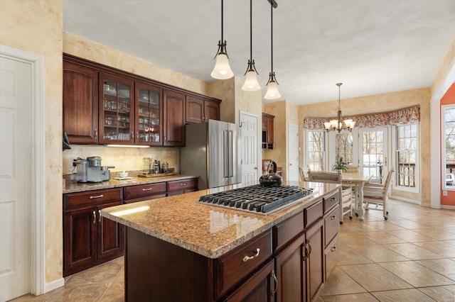 kitchen with a center island, decorative light fixtures, stainless steel appliances, dark brown cabinets, and light stone countertops