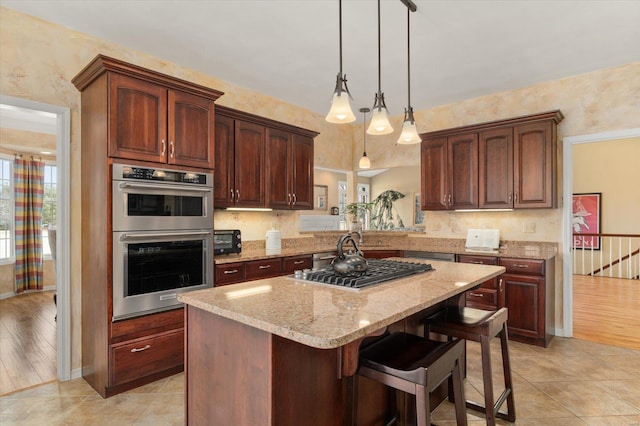 kitchen featuring light stone counters, stainless steel appliances, a center island, a kitchen bar, and decorative light fixtures