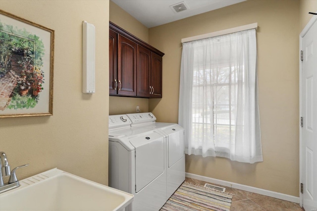 clothes washing area featuring washing machine and dryer, visible vents, cabinet space, and a sink