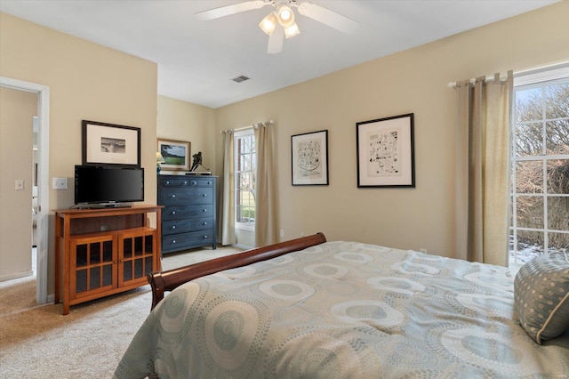 bedroom with light carpet, visible vents, and a ceiling fan