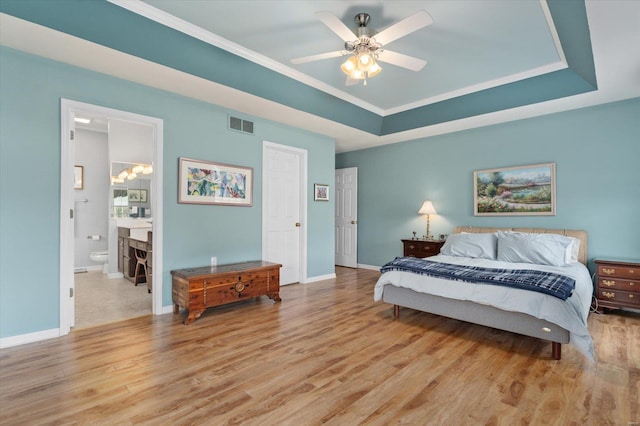 bedroom featuring baseboards, a raised ceiling, visible vents, and light wood-style floors