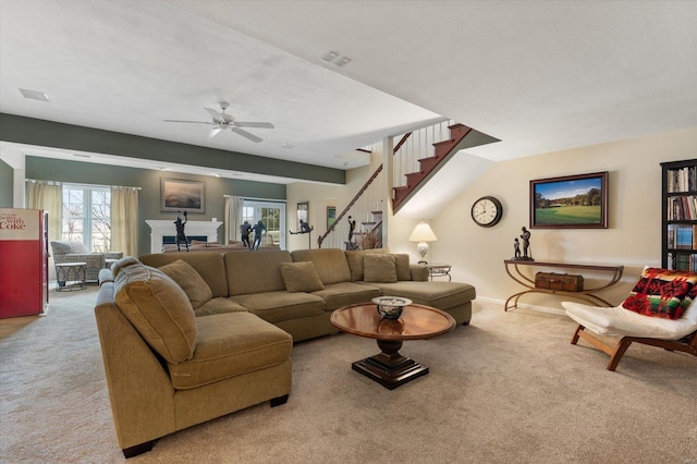 living room featuring light colored carpet, visible vents, ceiling fan, baseboards, and stairs