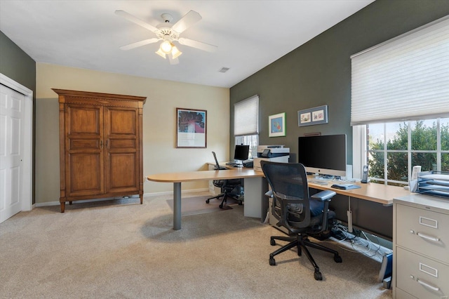 office space with baseboards, a healthy amount of sunlight, a ceiling fan, and light colored carpet