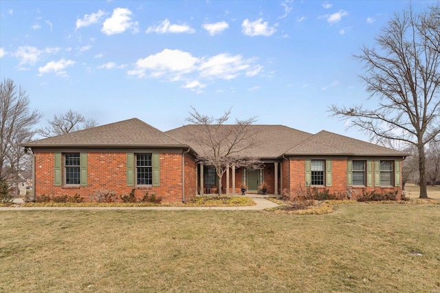 ranch-style home featuring roof with shingles, a front lawn, and brick siding