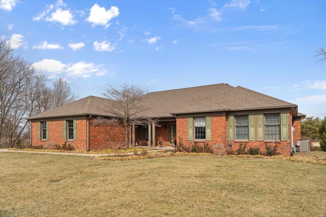 ranch-style home featuring a shingled roof, brick siding, a front lawn, and central air condition unit