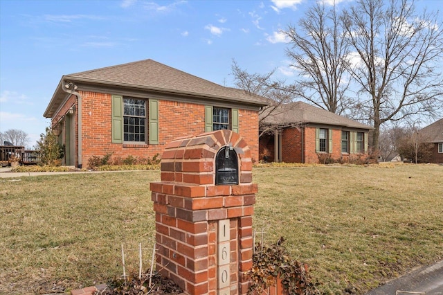 view of front facade with brick siding, roof with shingles, and a front yard