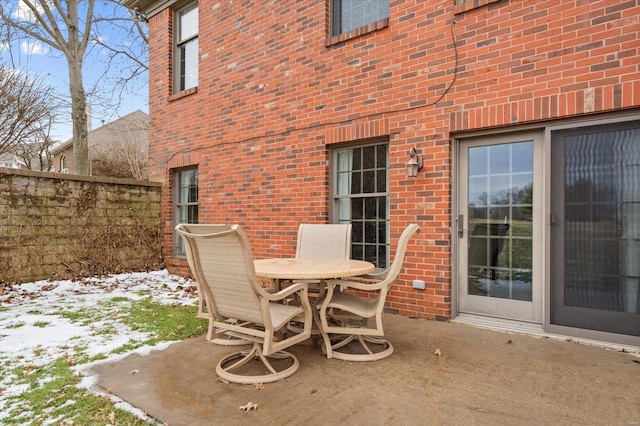 snow covered patio with outdoor dining space and fence