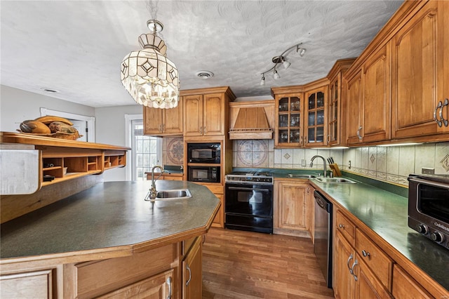 kitchen with dark countertops, black appliances, custom range hood, and a sink