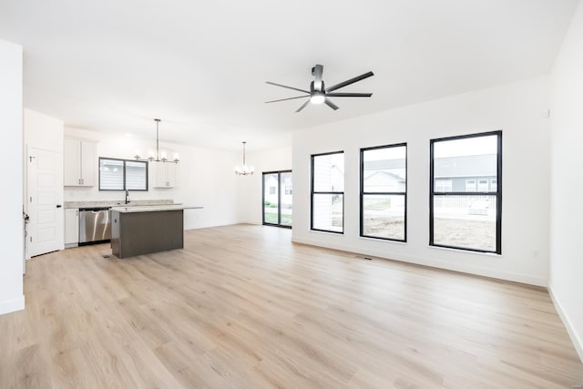 unfurnished living room with sink, ceiling fan with notable chandelier, and light hardwood / wood-style flooring