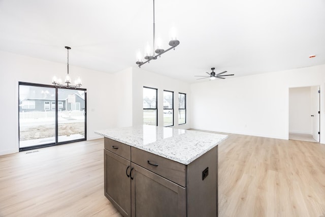 kitchen with pendant lighting, light stone countertops, light hardwood / wood-style floors, and a center island