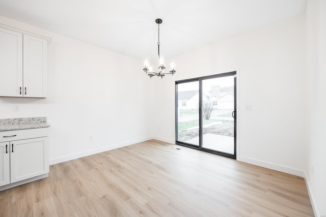 unfurnished dining area featuring a chandelier and light hardwood / wood-style flooring