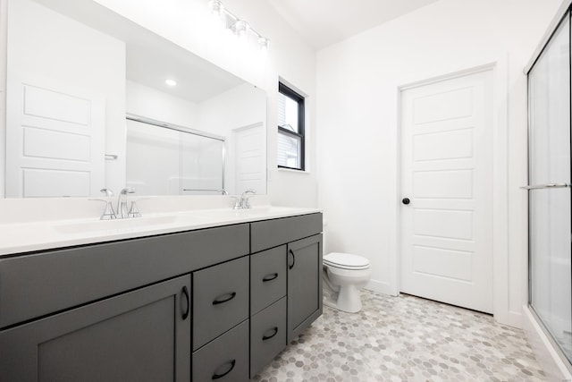 bathroom with a shower with door, vanity, and toilet