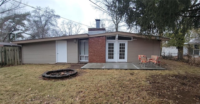 back of house with a yard, a chimney, a patio area, fence, and a fire pit