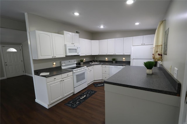 kitchen with dark countertops, white appliances, and white cabinetry