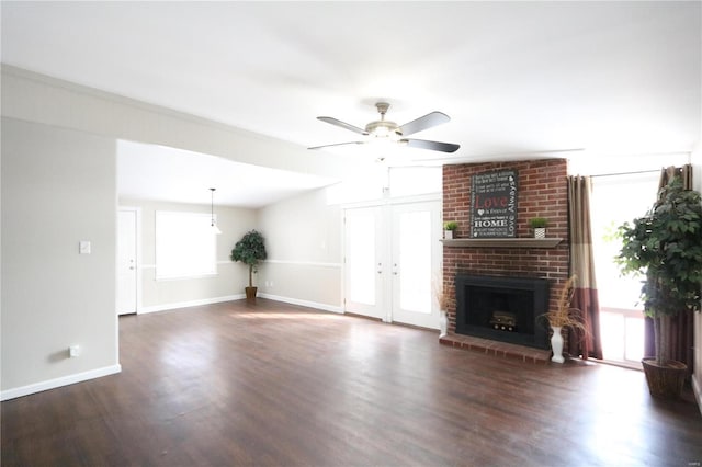 unfurnished living room with dark wood-style floors, a fireplace, ceiling fan, and baseboards