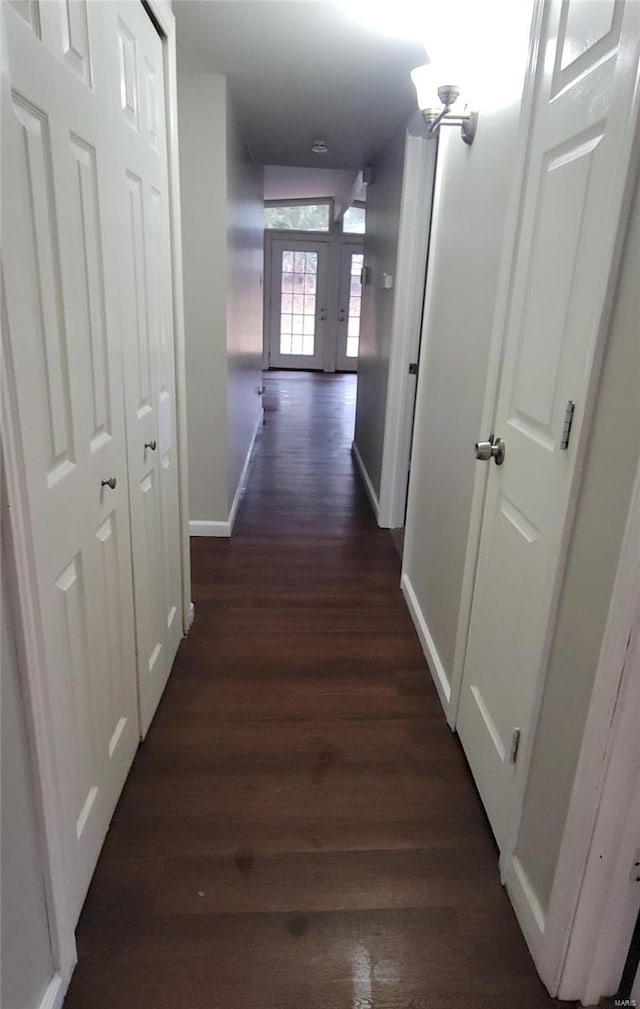 hall featuring dark wood-type flooring and baseboards