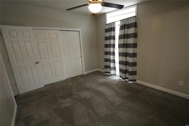 unfurnished bedroom with a ceiling fan, dark colored carpet, a closet, and baseboards