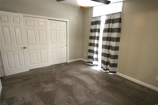 unfurnished bedroom featuring a ceiling fan, a closet, dark carpet, and baseboards