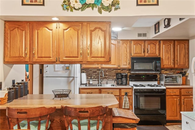 kitchen with tasteful backsplash, sink, range with gas stovetop, and refrigerator