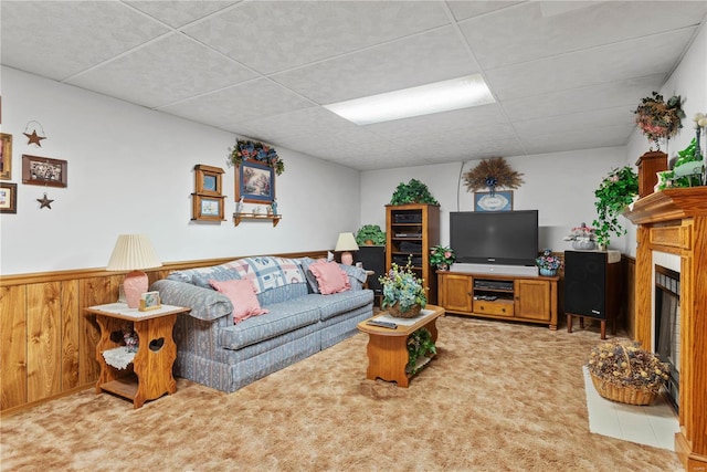 living room featuring a drop ceiling and wooden walls