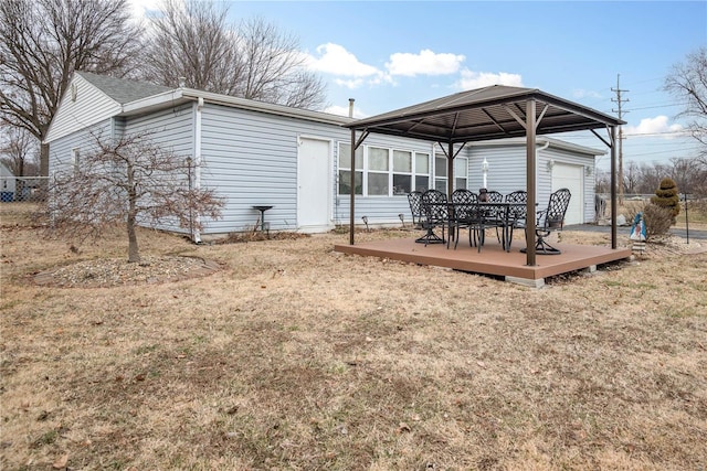 back of property featuring a garage, a gazebo, a wooden deck, and a lawn