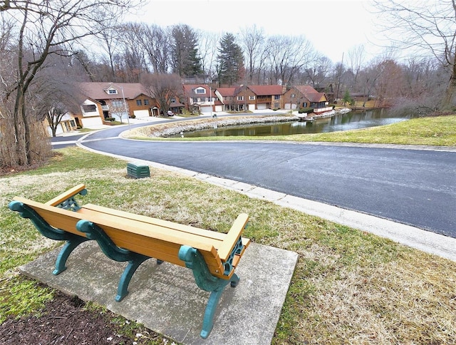 view of road with a residential view, a water view, and curbs