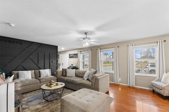 living room featuring ceiling fan, wood-type flooring, and a textured ceiling