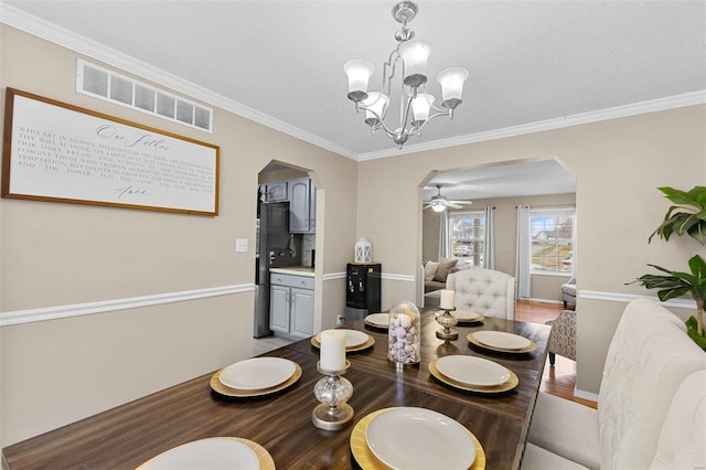 dining room with an inviting chandelier, ornamental molding, light hardwood / wood-style floors, and a textured ceiling