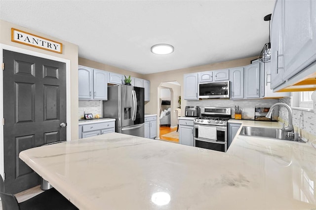 kitchen featuring sink, appliances with stainless steel finishes, tasteful backsplash, a kitchen bar, and kitchen peninsula