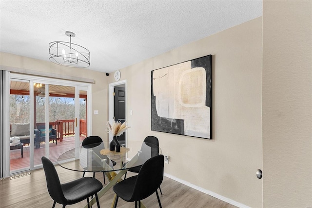 dining room featuring hardwood / wood-style flooring, an inviting chandelier, and a textured ceiling