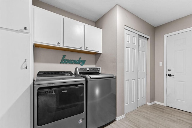 washroom featuring cabinets, washer and clothes dryer, and light wood-type flooring