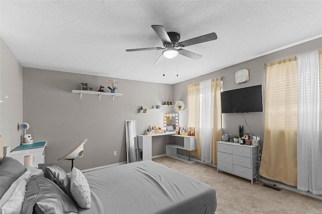 carpeted bedroom with ceiling fan and a textured ceiling