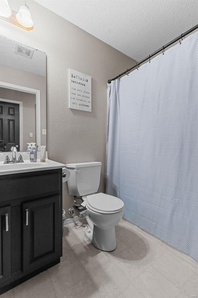 bathroom with vanity, tile patterned floors, toilet, and a textured ceiling