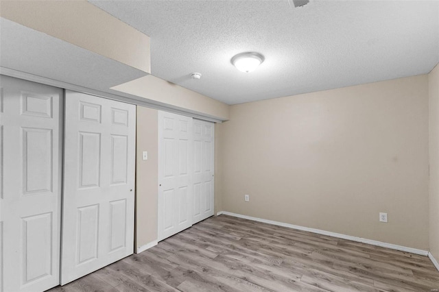 unfurnished bedroom featuring a textured ceiling, light wood-type flooring, and a closet