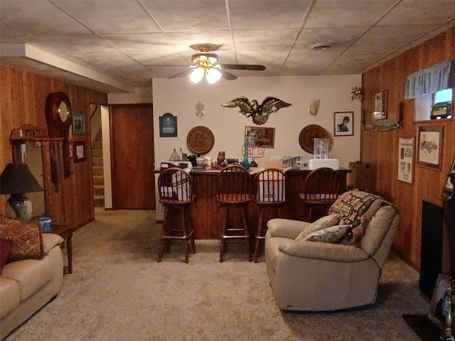 living room featuring ceiling fan, carpet floors, bar area, and wooden walls