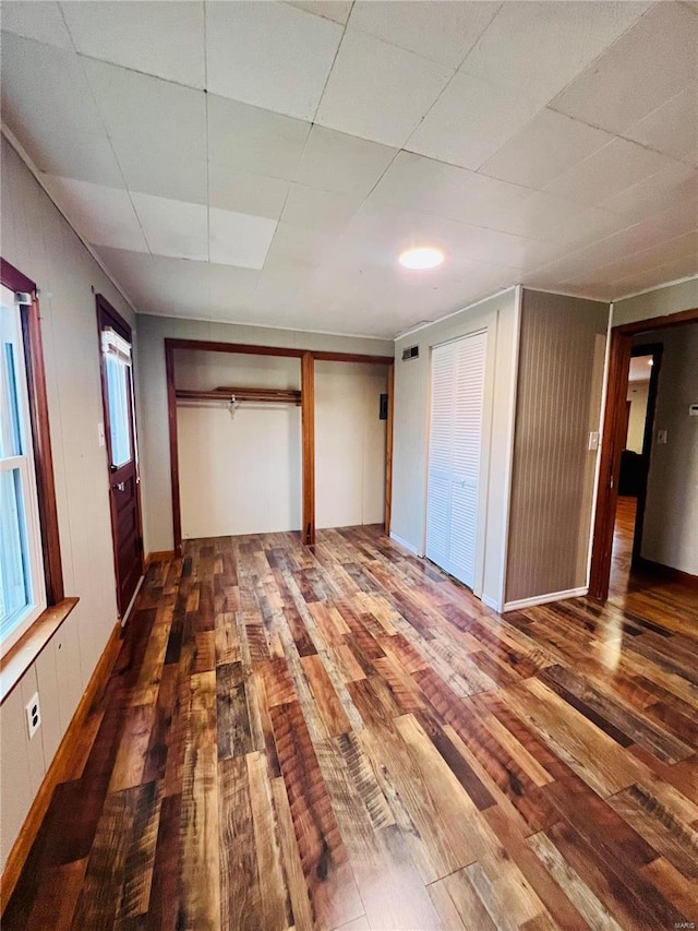 unfurnished bedroom featuring hardwood / wood-style flooring and multiple closets