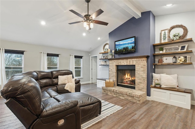 living room with a fireplace, ceiling fan, vaulted ceiling with beams, and hardwood / wood-style floors