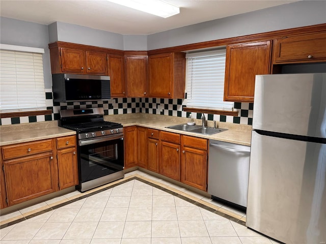 kitchen featuring stainless steel appliances, sink, light tile patterned floors, and backsplash