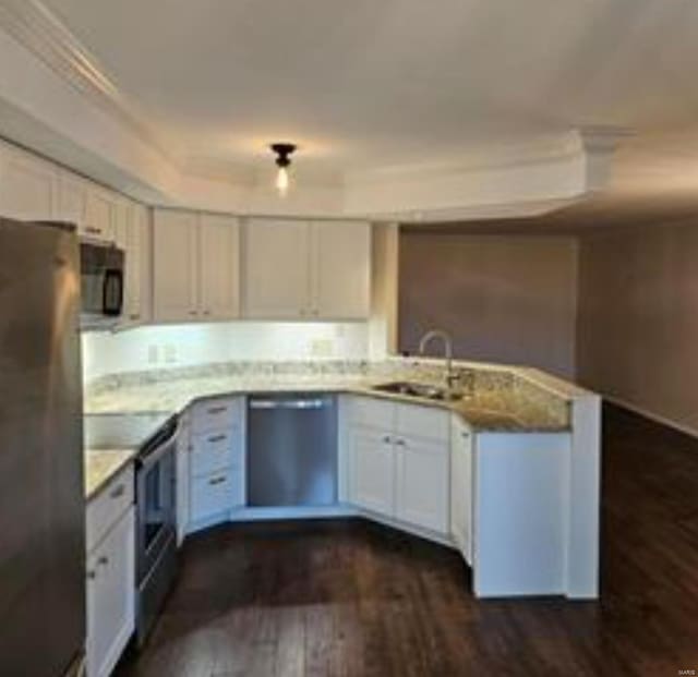 kitchen with sink, stainless steel appliances, dark hardwood / wood-style floors, a tray ceiling, and white cabinets