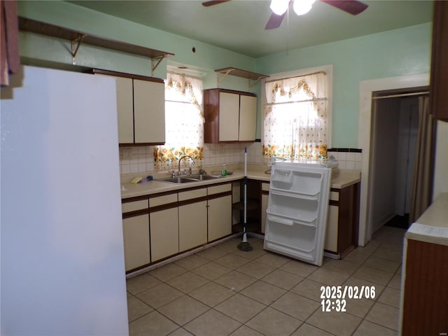 kitchen featuring sink, ceiling fan, backsplash, light tile patterned flooring, and white fridge